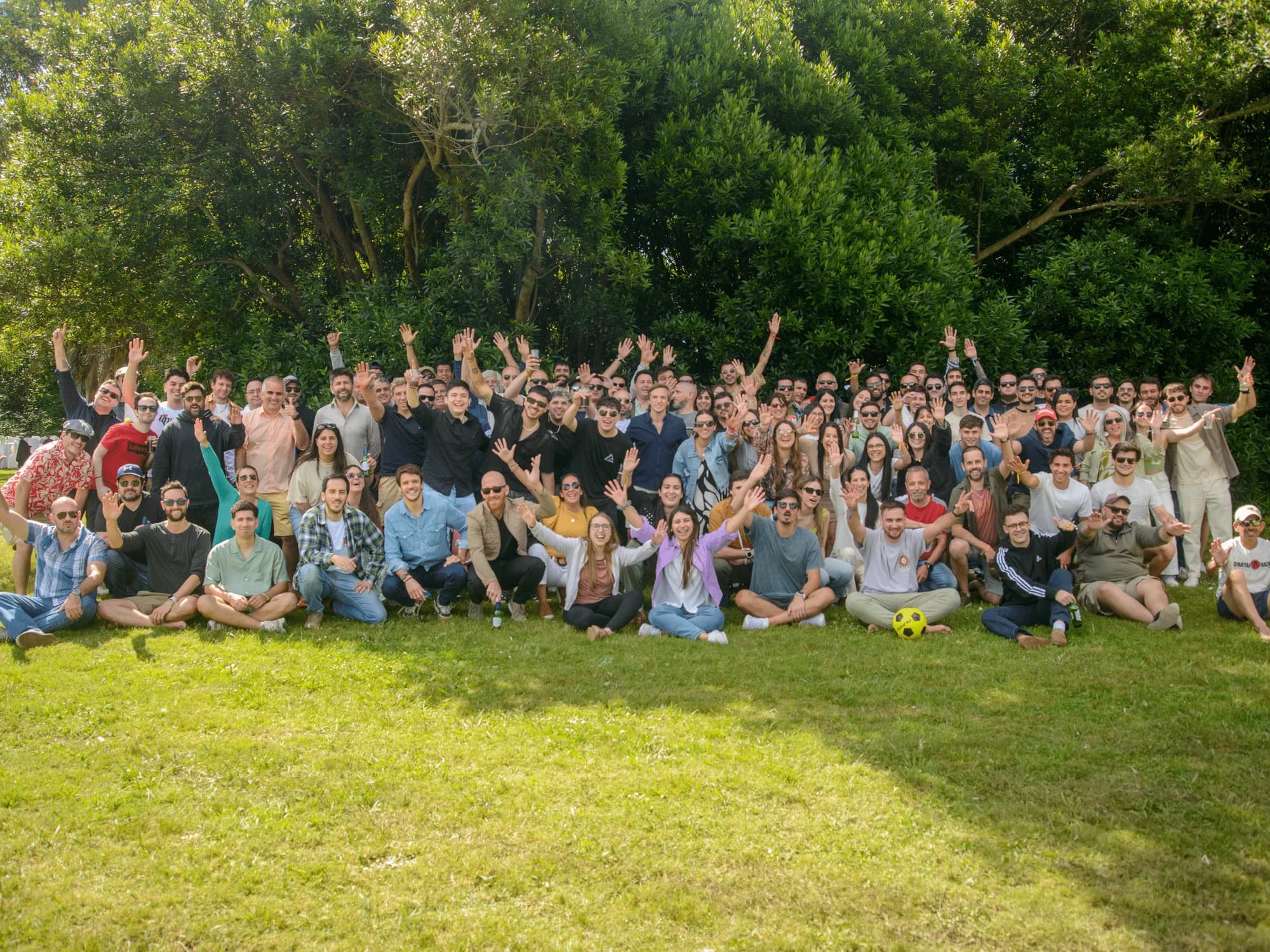 El equipo de Quantik al aire libre sobre el pasto, en varias filas, muchos con los brazos levantados y una arboleda detrás.